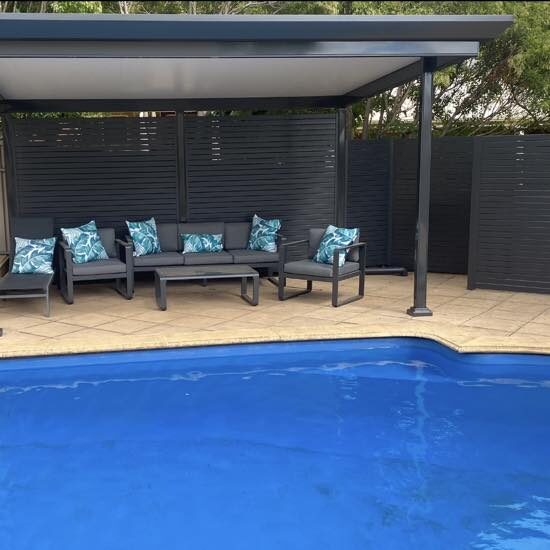 Pool lounge with outdoor blinds and teal cushions