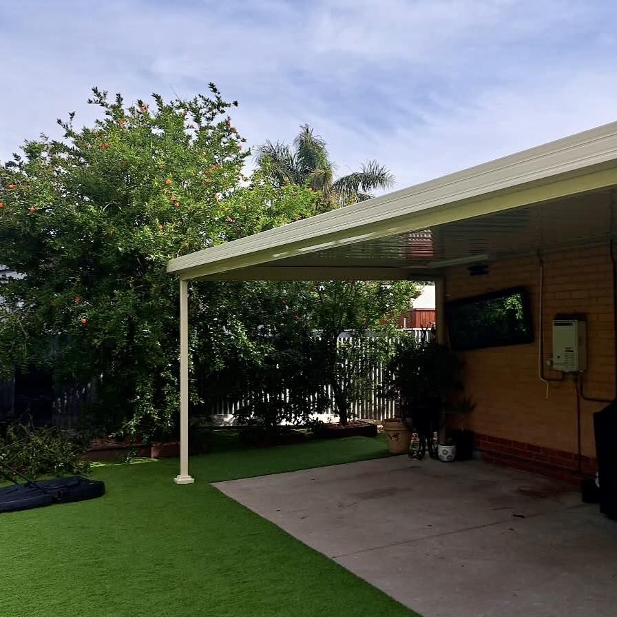 Carport shaded by trees over a grassed yard